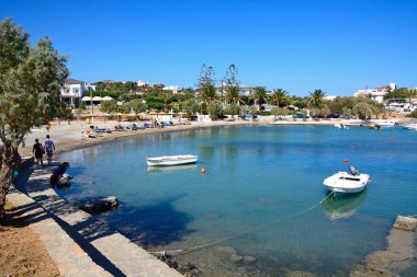 Arkaya, Agios Nikolaos, Crete sahilde rahatlatıcı turist ile St Nicolas Bay için yapılan küçük tekne palamarla.