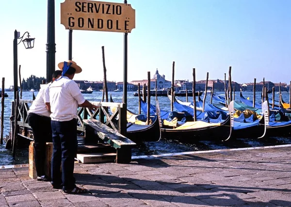 Gondoliers debout sur le front de mer par leurs gondoles le long du Grand Canal, Venise, Italie . — Photo