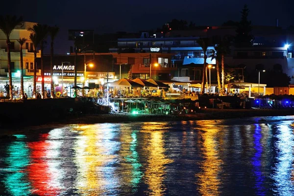 Blick auf den Strand und Geschäfte und Restaurants am Wasser in der Nacht, hersonissos, Beton. — Stockfoto