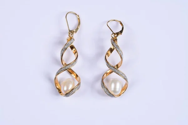 Gold and diamond twisted earrings with a large pearl inside against a white background. — Stock Photo, Image