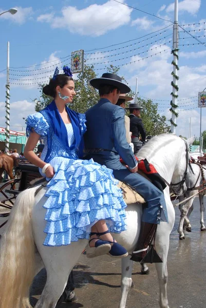 Coppia spagnola in abito tradizionale seduta su un cavallo con Casitas sul retro alla Fiera di Siviglia, Siviglia, Spagna . — Foto Stock