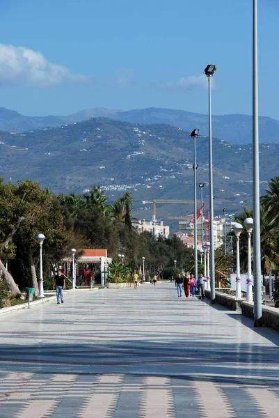 Vista a lo largo del paseo marítimo hacia las montañas con los turistas disfrutando del entorno, Torre del Mar, España . —  Fotos de Stock