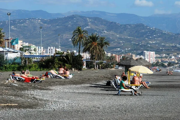 Turistas relajados en la playa con vistas hacia las montañas, Torre del Mar, España . — Foto de Stock