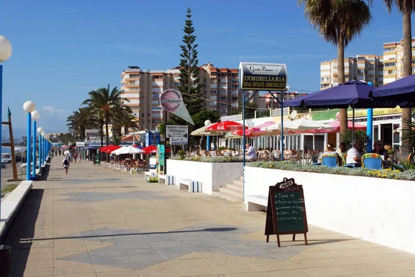 Turistas caminando a lo largo del paseo marítimo con cafés de pavimento a la derecha, Torrox Costa, España . — Foto de Stock