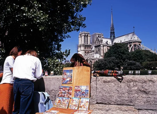 Utsikt över Notre Dame katedral med turister tittar på målningar på en bro i förgrunden, Paris, Frankrike. — Stockfoto