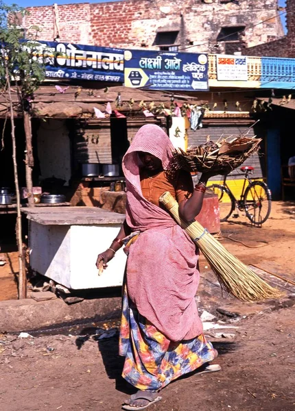 Indisk kvinna promenader längs en by shoppinggatan som bär en korg, Jaipura, Indien. — Stockfoto