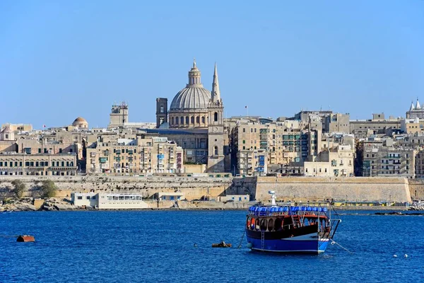 Utsikt över Valletta stadens byggnader och vattnet sett från hamnen Marsamxett med turbåt i förgrunden, Valletta, Malta. — Stockfoto
