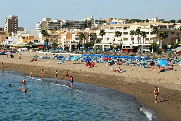 Turistas relajados en la playa con hoteles y apartamentos en la parte trasera, Torremolinos, España . — Foto de Stock