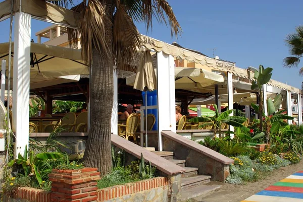 Turistas relajándose en un bar de playa a lo largo del paseo marítimo, Torremolinos, España . — Foto de Stock