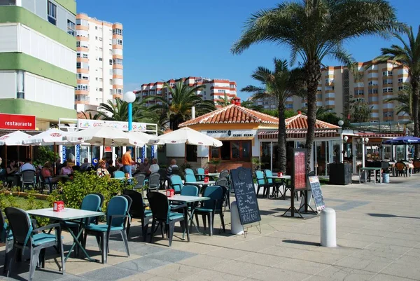 Turistas relajándose en los cafés de la acera a lo largo del paseo marítimo, Torrox Costa, España . — Foto de Stock