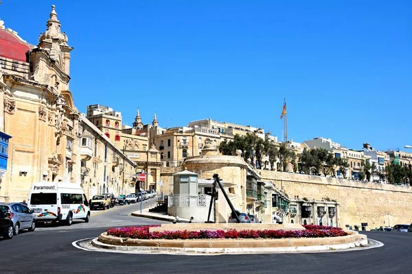 Verkehrsinsel mit Viktoriator, Kirche und Stadtgebäuden im Hintergrund, valletta, malta. — Stockfoto
