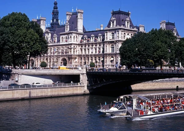 Hotel De Ville con un barco de recreo lleno de turistas en el río Sena en primer plano, París . — Foto de Stock