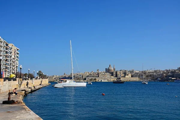 View of St Pauls Anglican Cathedral and the Basilica of Our Lady of Mount Carmel with a yacht in the foreground seen across the Grand Harbour from Sliema, Valletta, Malt. — Stock Photo, Image