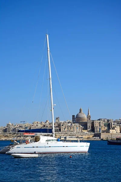 Utsikt över St Pauls Anglikansk katedral och de Basilica av vår fru av berget Karmel med en yacht i förgrunden sett över Grand Harbour från Sliema, Valletta, Malta. — Stockfoto