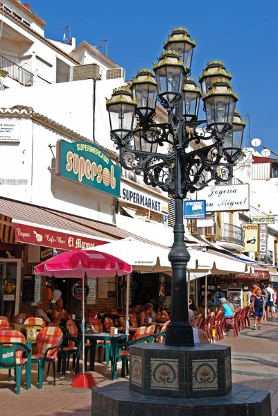 Ornate lamppost with pavement cafes to the rear along San Miguel street, Torremolinos, Spain. — Stock Photo, Image