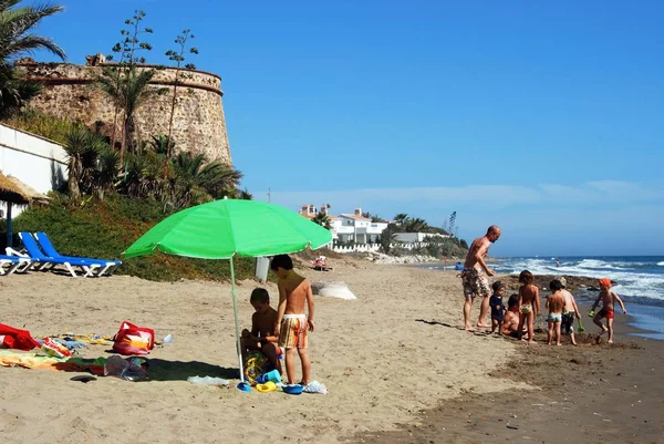 Turystów, relaks na plaży Playa de las Canas z starej wieży strażniczej do tyłu, Marbessa, Marbella, Hiszpania. — Zdjęcie stockowe