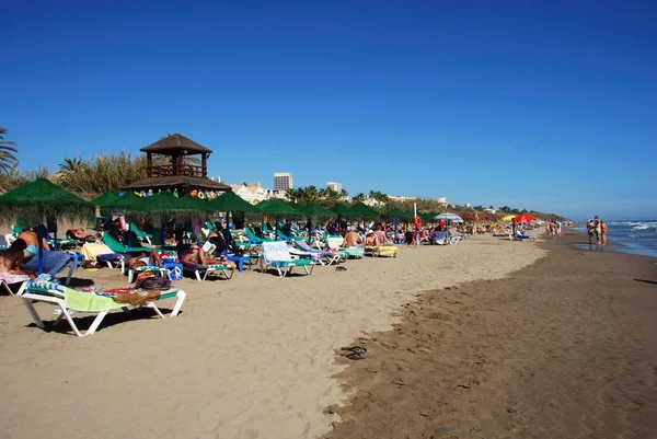 Tourists relaxing on Playa de la Vibora beach, Elviria, Marbella, Spain.