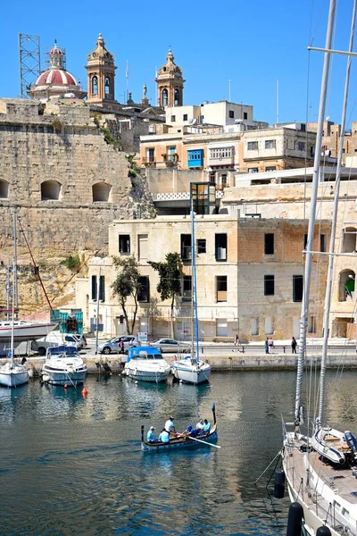 Passagiers aan boord van een traditionele Maltese Dghajsa water taxi in de haven met uitzicht op de waterkant Senglea, Vittoriosa, Malta. — Stockfoto