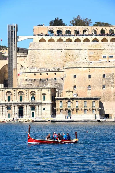Passengers on board a traditional Maltese Dghajsa water taxi in the grand harbour with views towards Upper Barrakka Gardens, Valletta, Malta — Stock Photo, Image