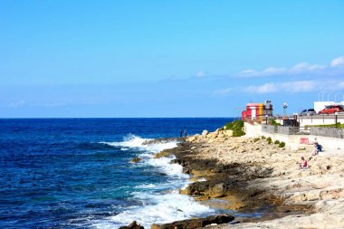 ourists rahatlatıcı kayalık sahil, Bugibba, Malta üzerinde.