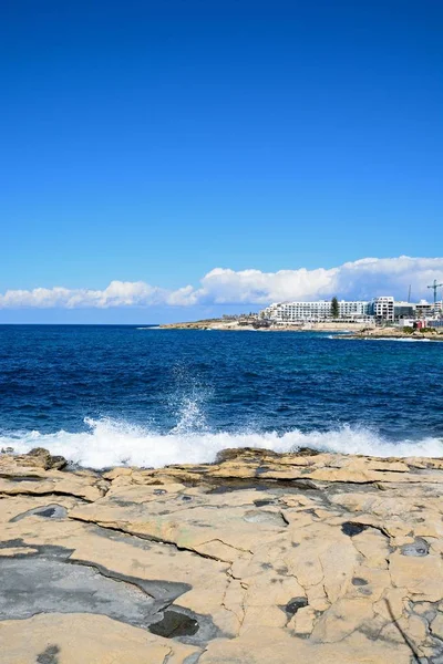 Moře na skalnatém pobřeží s hotely a apartmány dozadu, Bugibba, Malta. — Stock fotografie