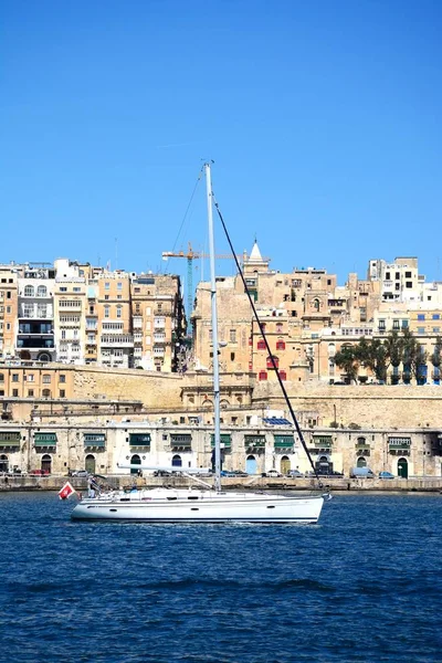 Valletta waterfront byggnader sett från över Grand Harbour i Vittoriosa med en yacht i förgrunden, Valletta, Malta. — Stockfoto