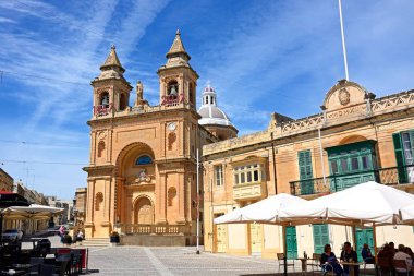 İnsanlar, kaldırım kafeleri ile parish Kilisesi Our Lady Pompei arka, Marsaxlokk, Malta için rahatlatıcı.