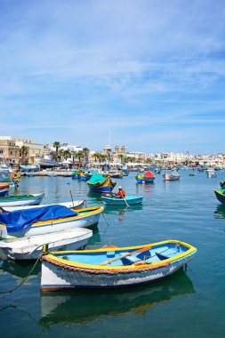 Geleneksel Malta Dghajsa balıkçı tekneleri ve liman waterfront binaları ile arka, Marsaxlokk, Malta.