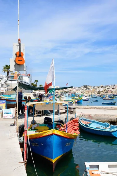 Tradycyjne maltańskie Dghajsa łodzie rybackie w porcie z nabrzeża budynków do tyłu, Marsaxlokk, Malta. — Zdjęcie stockowe