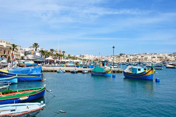 Geleneksel Malta Dghajsa balıkçı tekneleri ve liman waterfront binaları ile arka, Marsaxlokk, Malta. — Stok fotoğraf