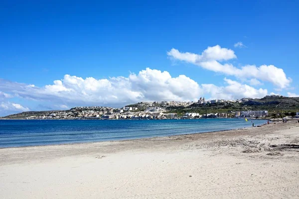 Iew de la playa de arena con edificios de la ciudad a través de la bahía, Mellieha, Malta . — Foto de Stock