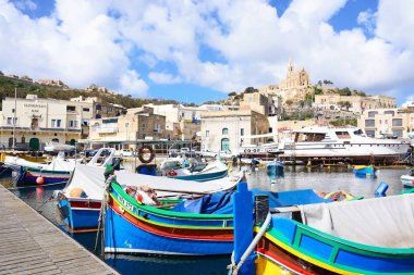 Geleneksel balıkçı tekneleri ve liman yamaca Lourdes Meryem Kilisesi ile arka, Mgarr, Gozo, Malta, Europe.