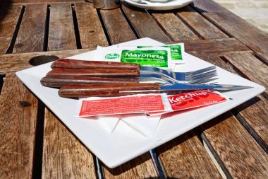 Çatal bıçak takımı, ketçap ve mayonez Kalesi, Victoria, Gozo içinde ahşap bir masa üzerinde paketler ile.