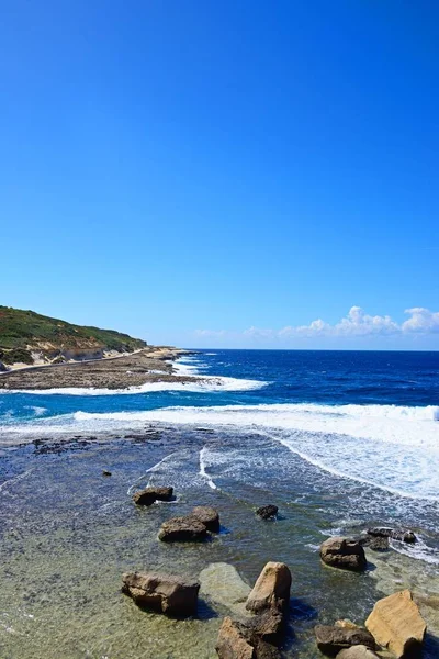 Zobrazit podél pobřeží s kameny v mělké vodě v popředí, Marsalforn, Gozo, Malta — Stock fotografie