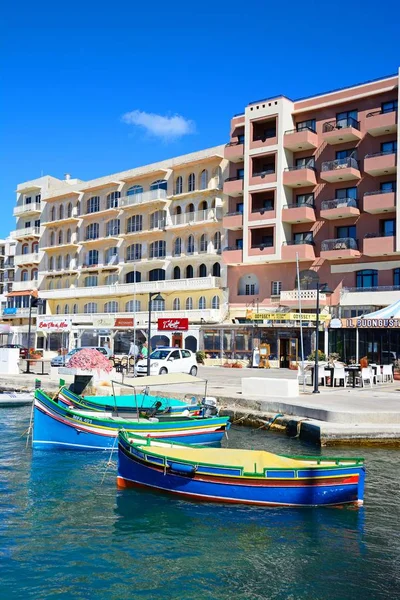 Barche da pesca tradizionali maltesi Dghajsa nel porto con bar e ristoranti sul retro, Marsalforn, Gozo, Malta . — Foto Stock