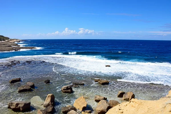 Zobrazit podél pobřeží s kameny v mělké vodě v popředí, Marsalforn, Gozo, Malta. — Stock fotografie
