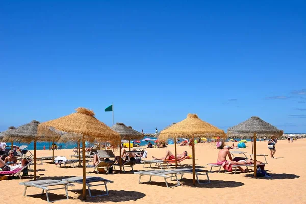 Turisti che si rilassano sulla spiaggia con vista verso i frangiflutti d'ingresso del porto, Vilamoura, Portogallo . — Foto Stock