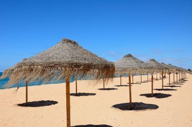 Rafya şemsiye arka, Vilamoura, Algarve, Portekiz için Atlantik Okyanusu ile sahilde satırları.