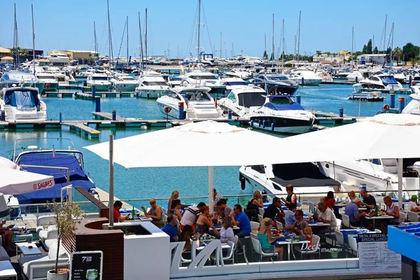 Barcos de luxo atracados na marina com restaurantes à beira-mar em primeiro plano, Vilamoura, Algarve, Portugal . — Fotografia de Stock