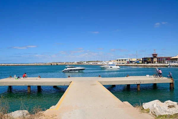 Locals on a concrete jetty at the harbour entrance with a boats passing by, Vilamoura, Algarve, Portugal. — Stock Photo, Image