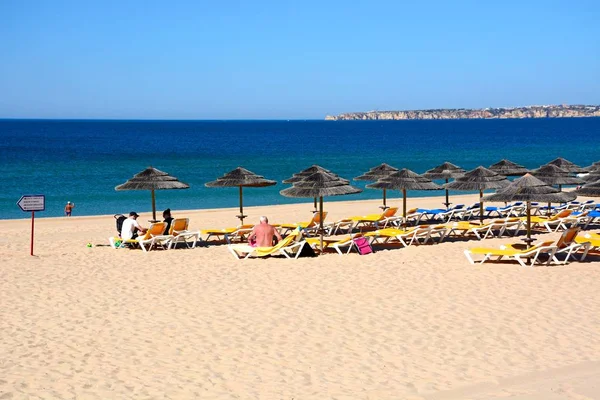 Relaxační turisté na písečné pláži s výhledem na Atlantský oceán a pobřeží, Alvor, Algarve, Portugalsko. — Stock fotografie
