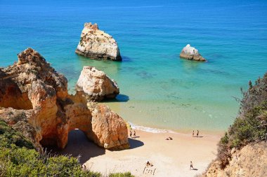 Turistler rahatlatıcı yükseltilmiş görünümünü sahilde büyük kayalar ile her iki taraf, Praia da Rocha, Portugal.