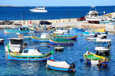 Traditional Maltese Dghajsa fishing boats moored in the harbour with views towards the coastline, San Pawl, Malta. clipart
