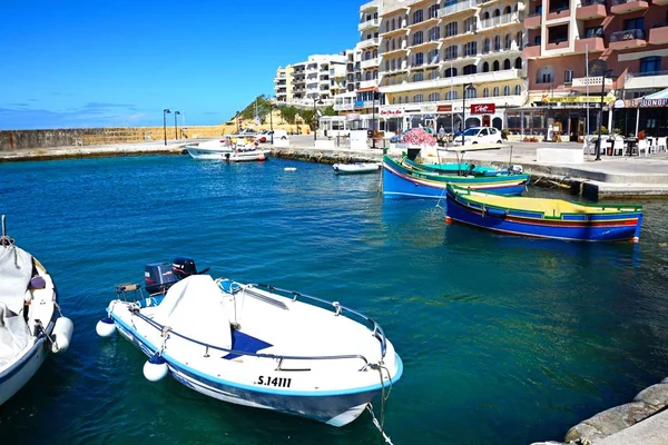Barcos de pesca tradicionales malteses Dghajsa en el puerto con bares y restaurantes en la parte trasera, Marsalforn, Gozo, Malta . — Foto de Stock