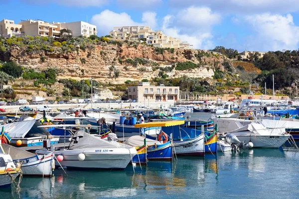 Vista dos tradicionais barcos de pesca malteses Dghajsa e barcos modernos no porto com apartamentos na encosta para trás, Mgarr, Gozo, Malta . — Fotografia de Stock