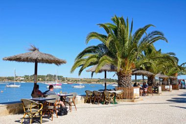 Turist alan gezinti yolu üzerinde yatların manzarasına sahip bir kaldırım kafede dinlendirici Haliç, Alvor, Portekiz demirleyen.