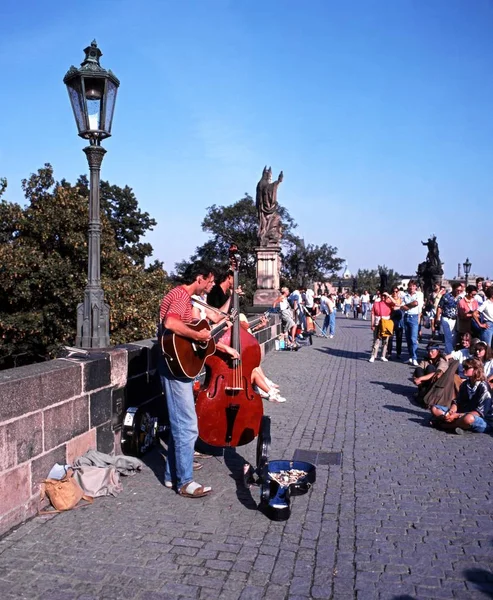 Turistas escuchando músicos callejeros en el Puente de Carlos, Praga, República Checa . — Foto de Stock