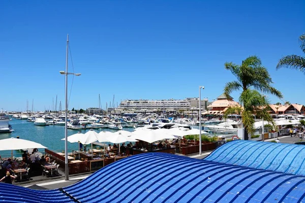 Luxe boten afgemeerd in de jachthaven met waterkant restaurants op de voorgrond, Vilamoura, Portugal. — Stockfoto