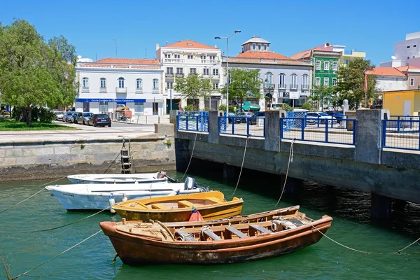 Pequenos barcos atracados contra uma ponte no rio Arade com edifícios da cidade para a retaguarda, Portimão, Portugal . — Fotografia de Stock