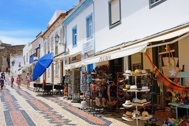 Dükkan ve kaldırım kafeleri R 25 de Abril alışveriş caddesi Lagos, Algarve, Portekiz tarafından geçen turistler ile eski şehir boyunca.